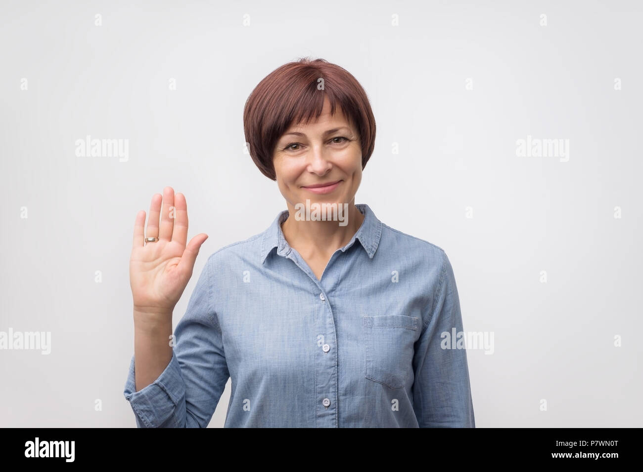 Caucasian woman smiling mature positif et amical en agitant la main en appareil photo. Banque D'Images