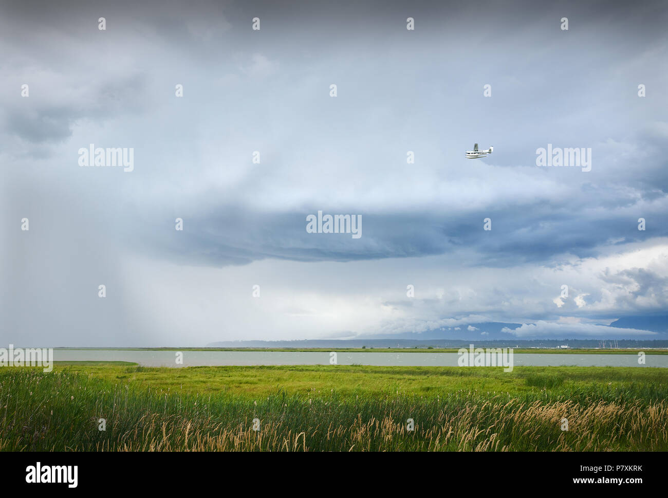 Un avion vole dans les nuages de tempête et de la pluie sur la rivière Fraser et de l'aéroport de Vancouver. Banque D'Images
