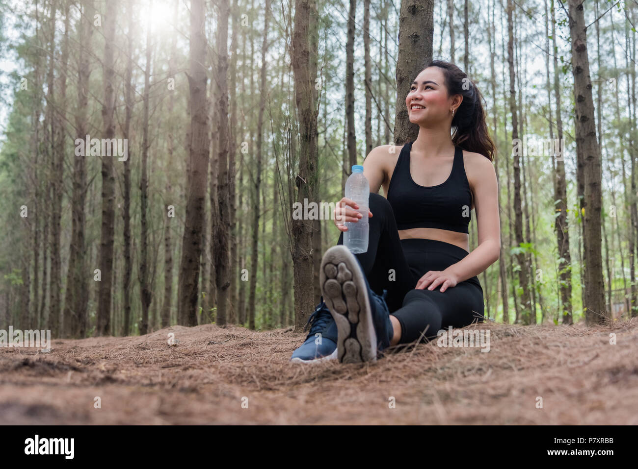 Sport femme asiatique de beauté et de repos holding drinking water bottle et reposant au milieu de la forêt après avoir fatigué de marcher. Fille assise et à la Banque D'Images