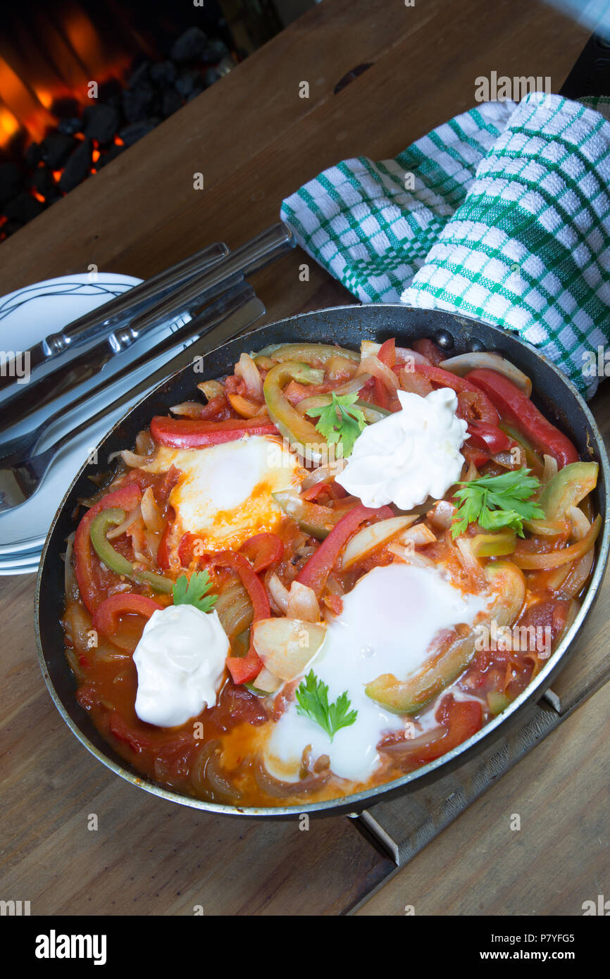 Un petit-déjeuner turc traditionnel plat de sautés à l'oignon, les poivrons et tomates avec oeuf poché et yogourt. Menemen. Banque D'Images