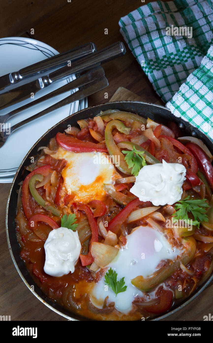 Un petit-déjeuner turc traditionnel plat de sautés à l'oignon, les poivrons et tomates avec oeuf poché et yogourt. Menemen. Banque D'Images