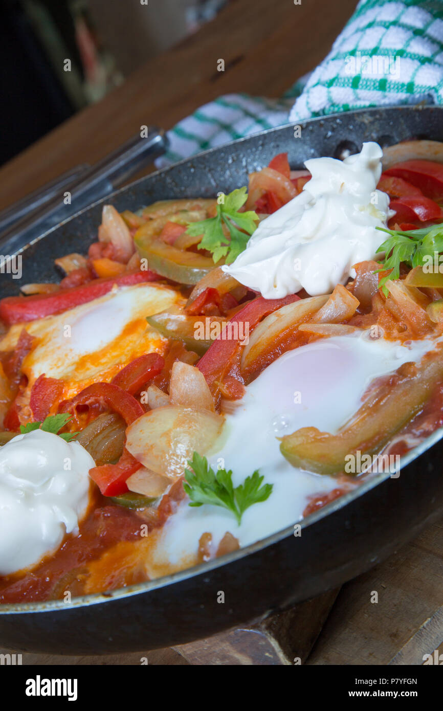 Un petit-déjeuner turc traditionnel plat de sautés à l'oignon, les poivrons et tomates avec oeuf poché et yogourt. Menemen. Banque D'Images