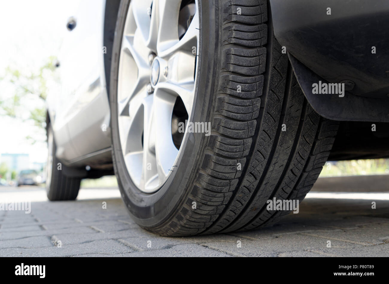 Location de pneu toutes saisons close up, voiture en stationnement. Low angle shot, roue auto avec jante aluminium concept Banque D'Images