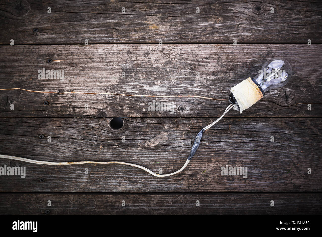 Concept - la négligence de la sécurité incendie. Retro lampe à incandescence avec fils endommagés et l'isolement par ruban électrique, sur fond de bois vintage avec l'espace Banque D'Images