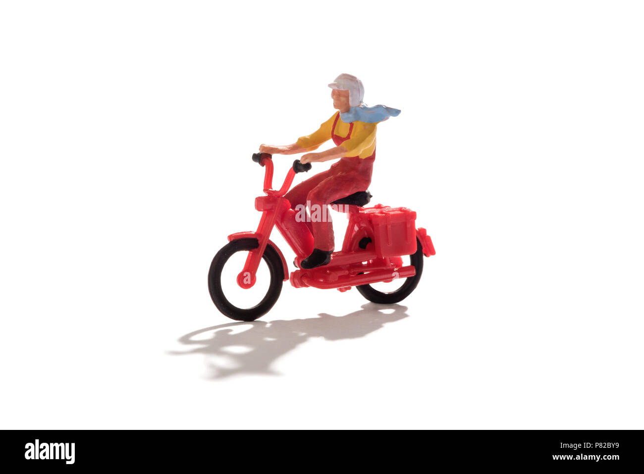 Homme miniature avec écharpe battant derrière lui une équitation moto rouge isolé sur blanc avec copie espace et l'ombre Banque D'Images