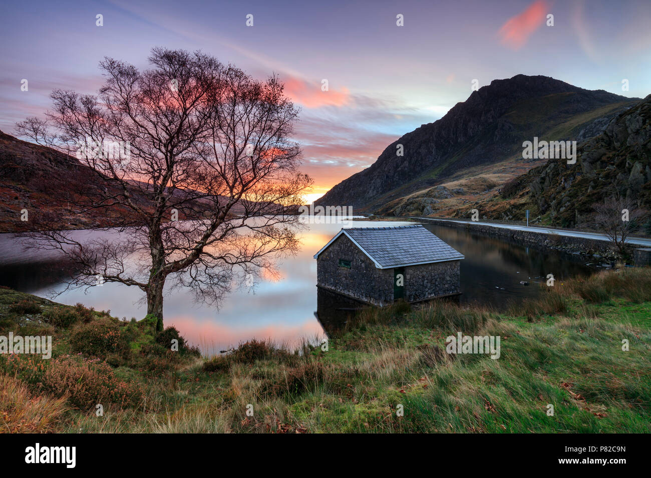 Les bateaux sur LLyn Ogwen capturé au lever du soleil avec au loin. Tryfan Banque D'Images