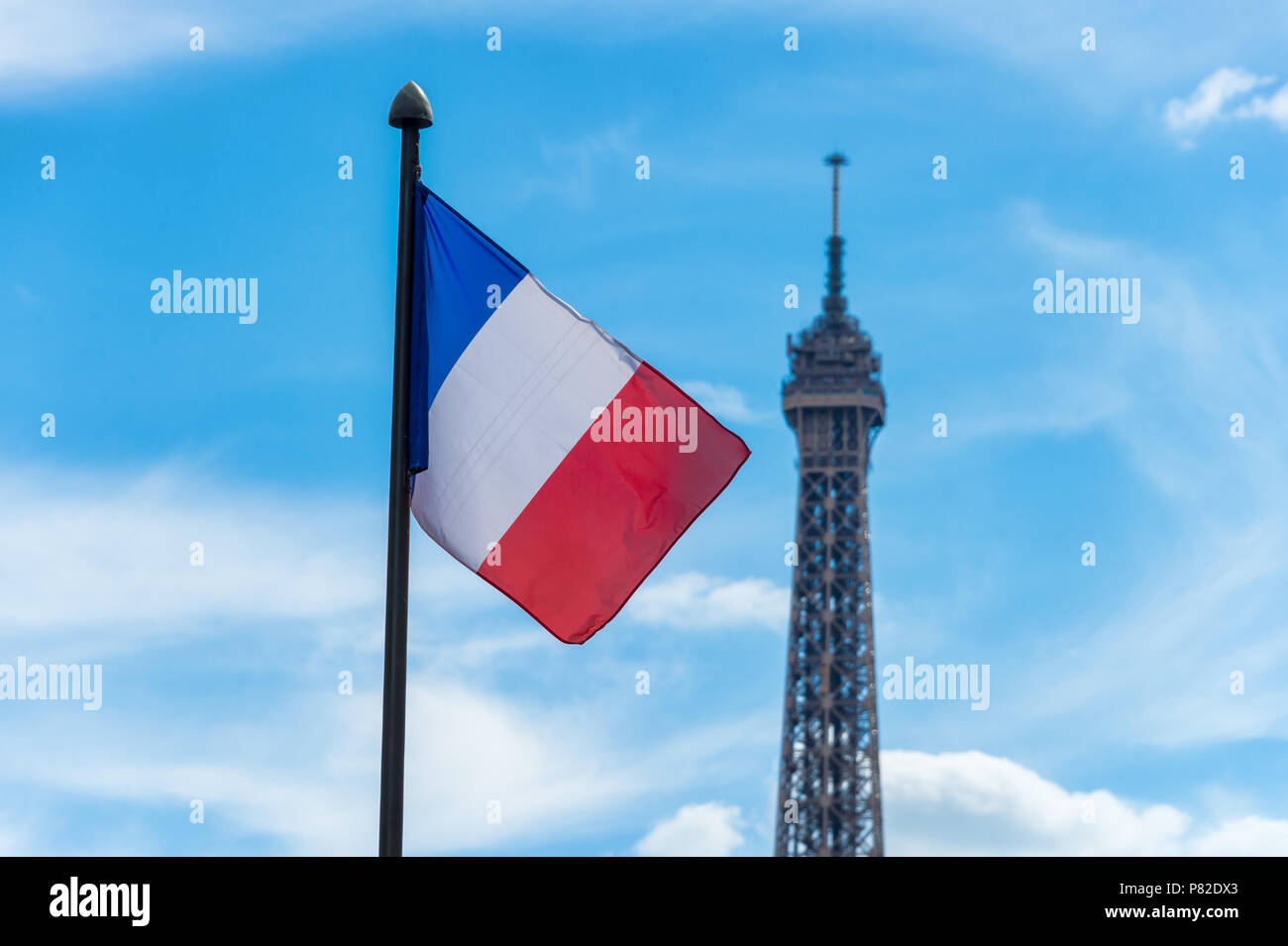 Brandir le drapeau français sur fond de ciel bleu et de la Tour Eiffel Banque D'Images
