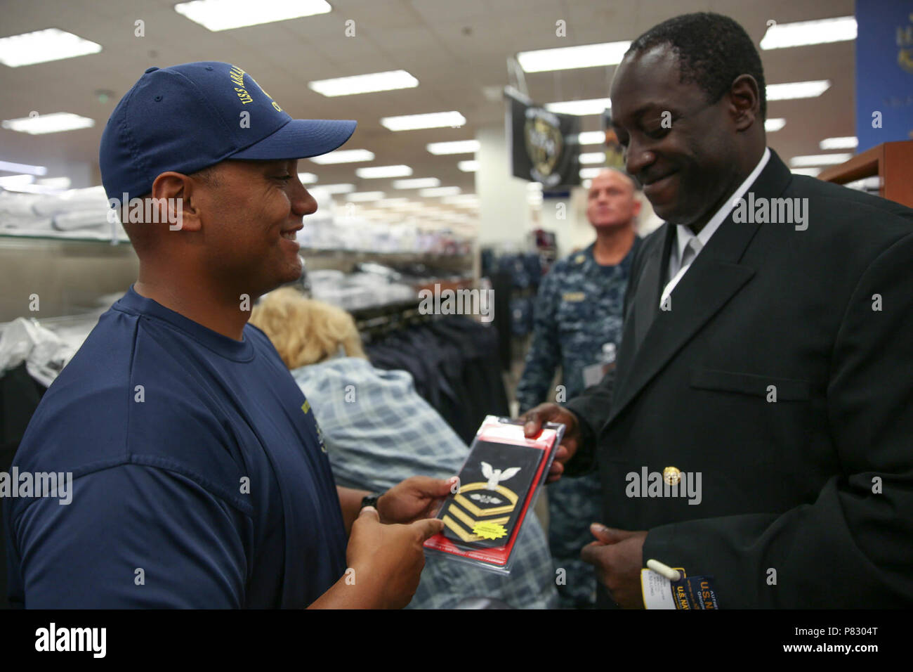 La NORFOLK (Août 18, 2016) Les cadres supérieurs de l'aviation en chef Maître de Manœuvre (manutention) Donovan Mahiai, assigné à la classe Nimitz porte-avions USS ABRAHAM LINCOLN (CVN 72) Aviation, chef Maître de Manœuvre (manutention) (sélectionnez) Bryan Hamilton son nouveau classement patch à Norfolk Naval Station Marine de l'uniforme change shop. Raccord uniforme, un événement CPO 365 Phase II, a marqué la première fois que le chef de l'Harem essayé sur l'uniforme de leur nouveau grade. Banque D'Images