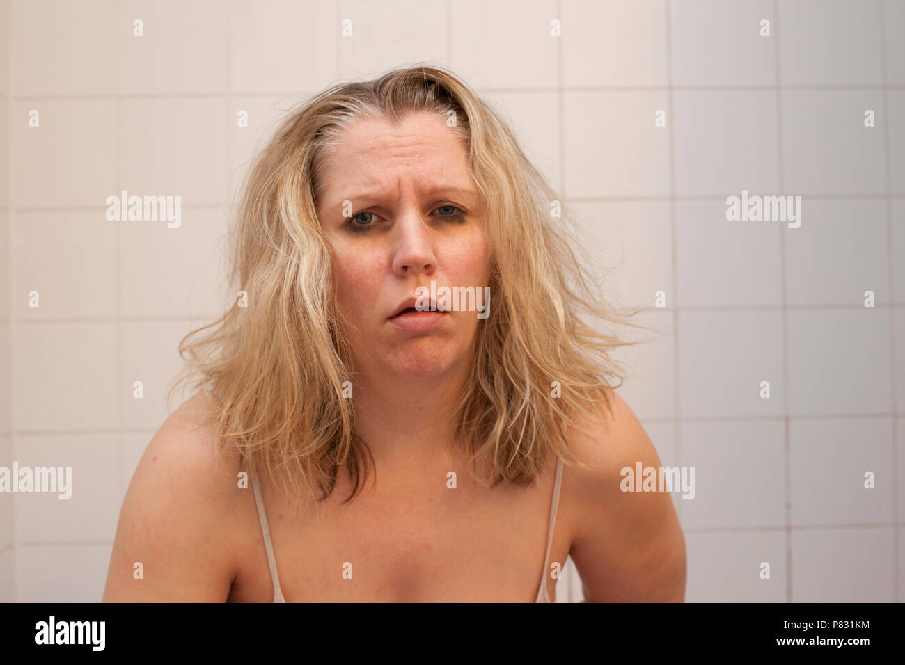 Femme aux yeux bleus et noir de cheveux en désordre regarde comme elle est prête à être malade ou vomir Banque D'Images