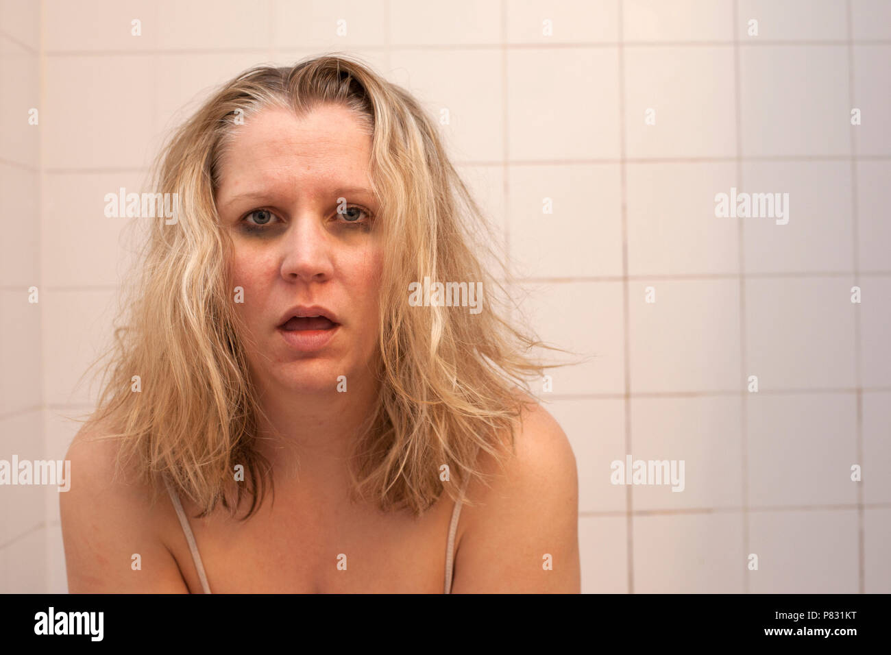 Une femme avec des cheveux en désordre horrible, sombres cercles noirs sous les yeux et à la face rugueuse se sent malade, gueule de bois ou de mauvais Banque D'Images