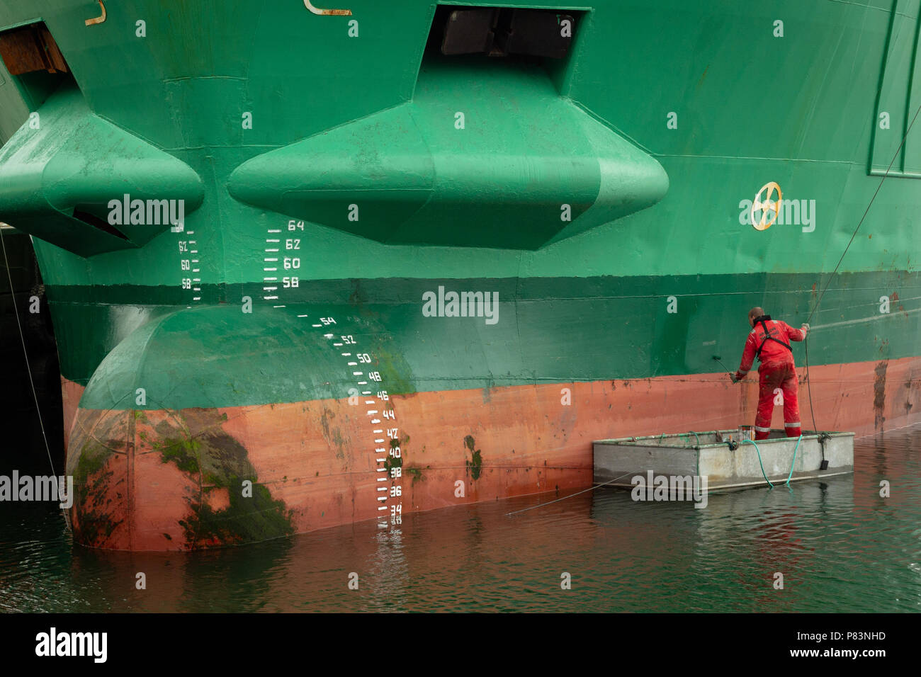 Kinsale, Comté, Cork, Irlande. Peinture rouge sur un grand navire de cargaison de couleur verte avec un petit rouleau de peinture. Banque D'Images