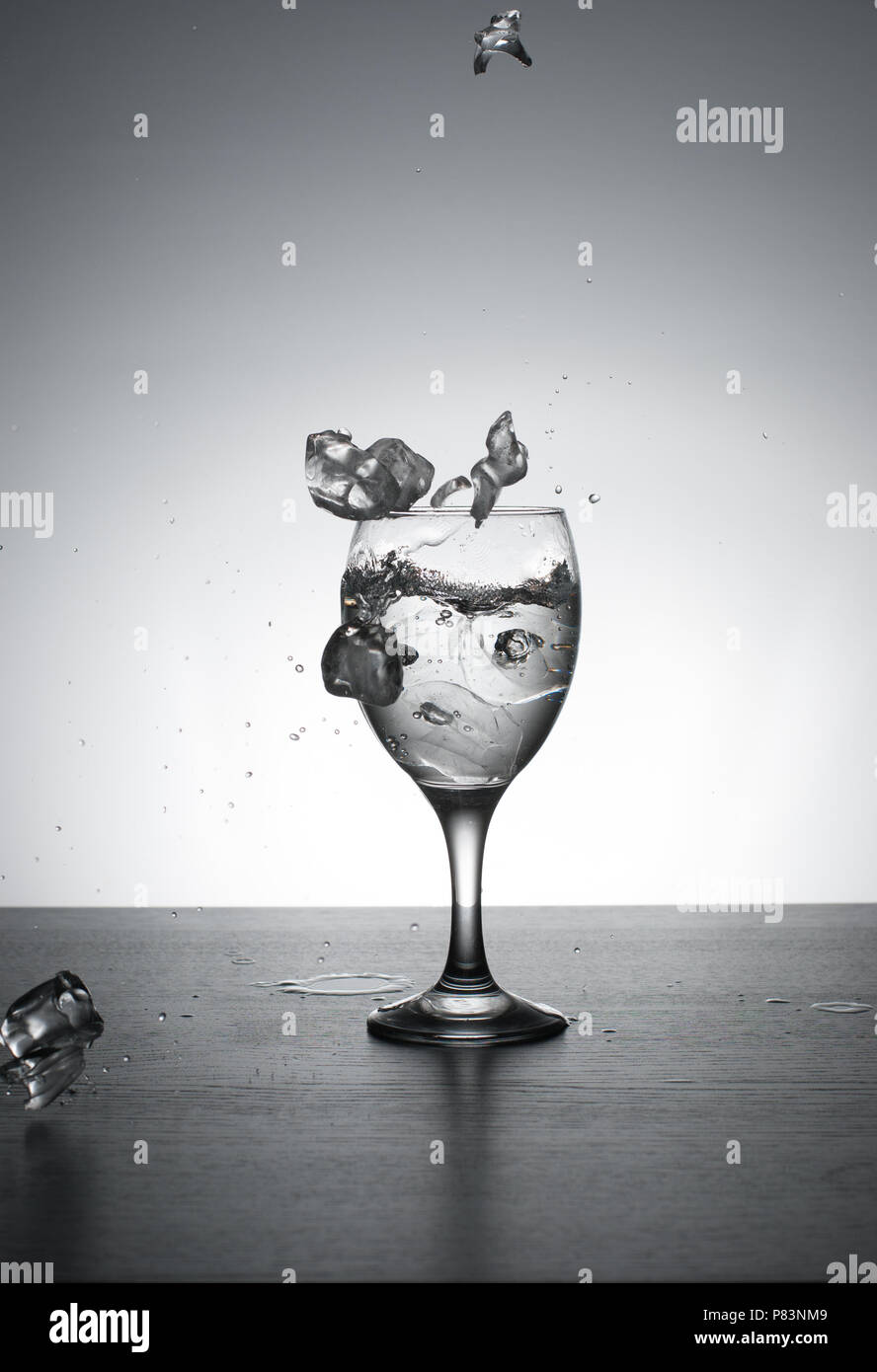 L'eau est versée dans le verre de vin, rétroéclairé sur fond blanc avec des touches.Vitesse d'obturation. Motion gelée. Banque D'Images