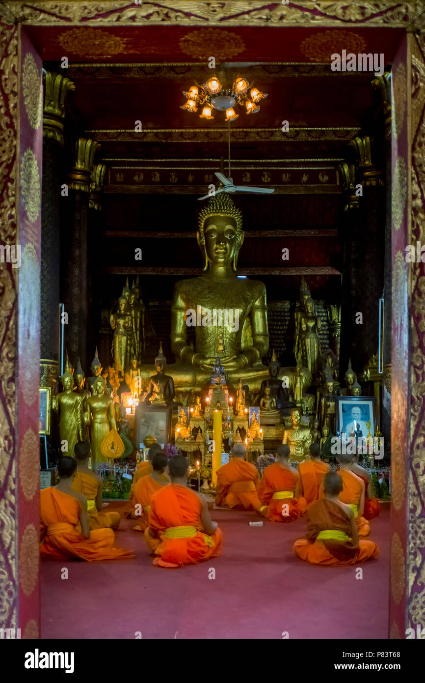 Les jeunes moines bouddhistes prient à l'intérieur d'un temple à Luang Prabang, Laos Banque D'Images