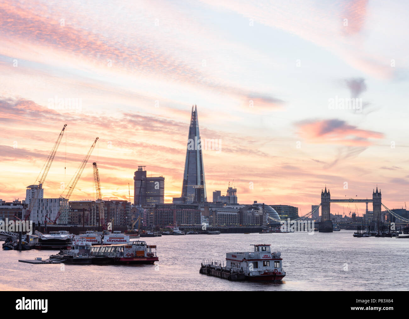 Coucher de soleil derrière le tesson et le Tower Bridge à Londres tourné de Bermondsey et avec des barges et des croisières sur la Tamise Banque D'Images