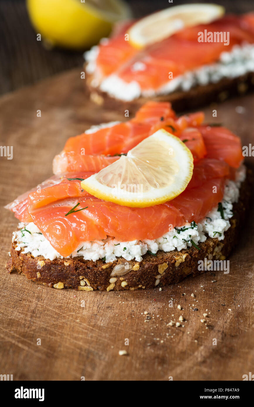 Sandwich au saumon savoureux avec du fromage à la crème et tranche de citron sur planche de bois, vue rapprochée, selective focus Banque D'Images