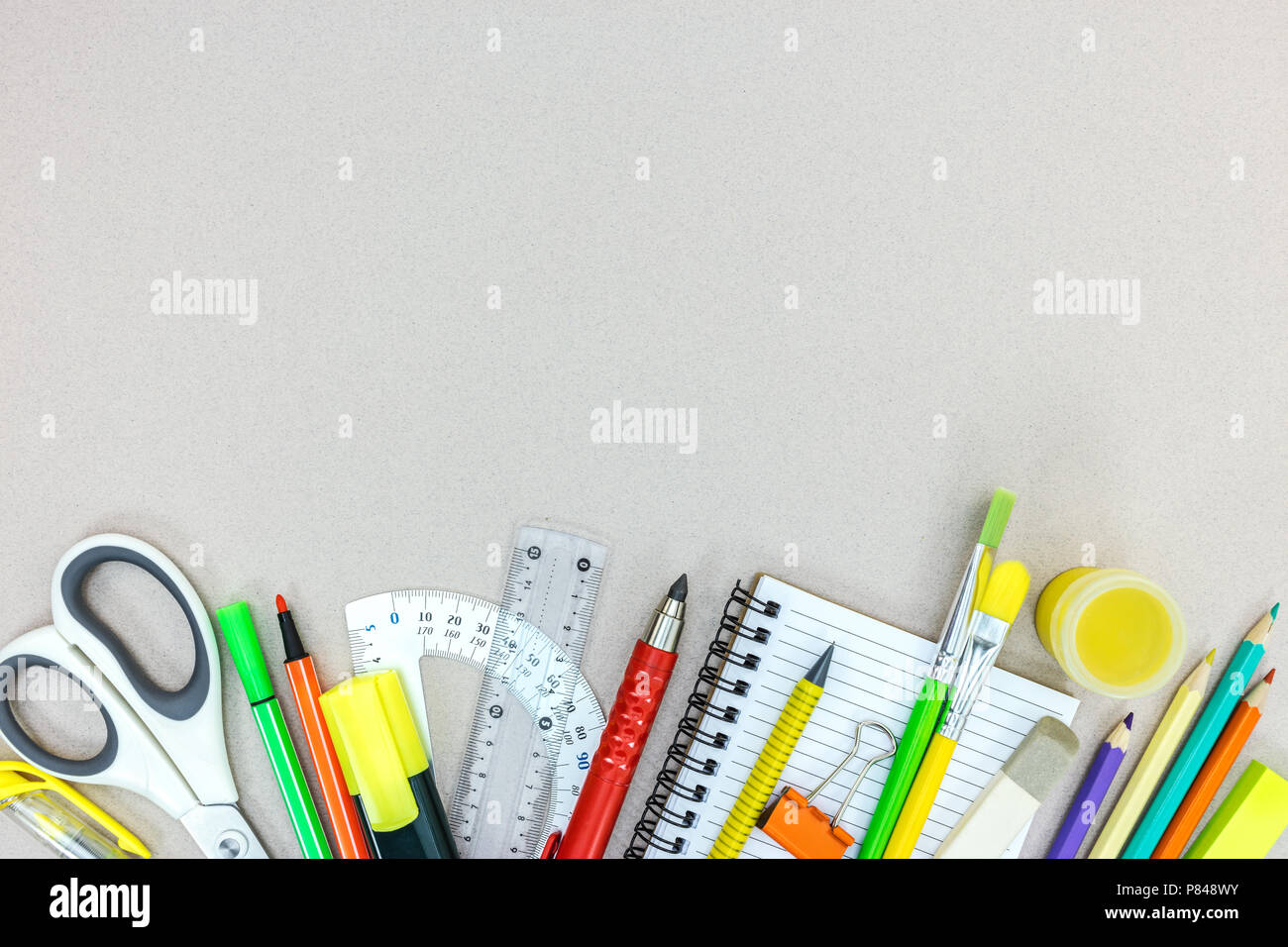 Variété de fournitures scolaires avec crayons, marqueurs, ordinateur portable sur fond gris. vue plate Banque D'Images