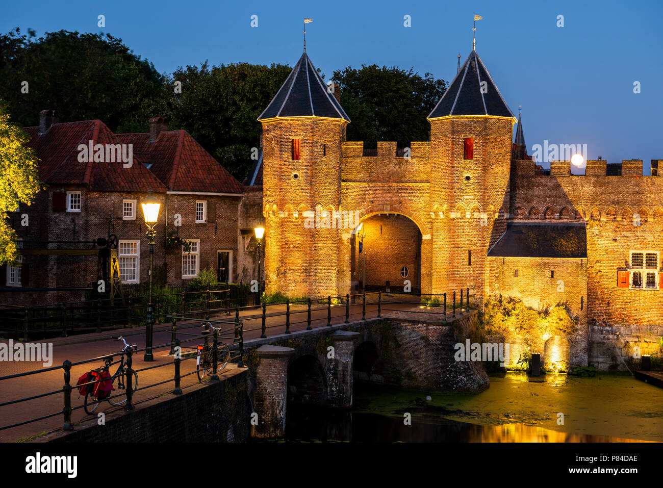 Koppelpoort dans la soirée avec deux llighted lampadaires, rue sombre et pleine lune. Banque D'Images