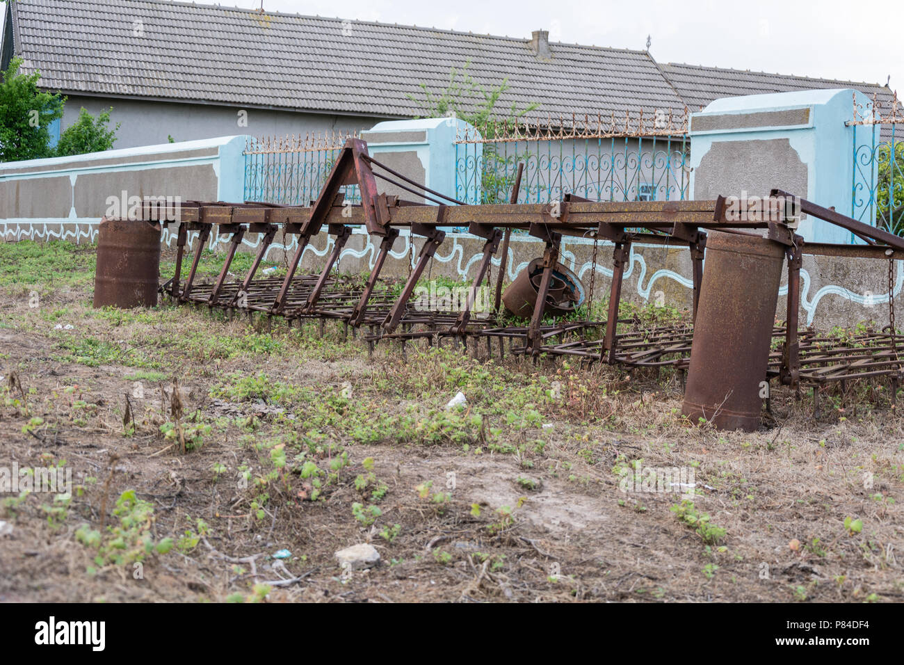 Vieille charrue rouillée près d'une clôture sur l'herbe sèche Banque D'Images