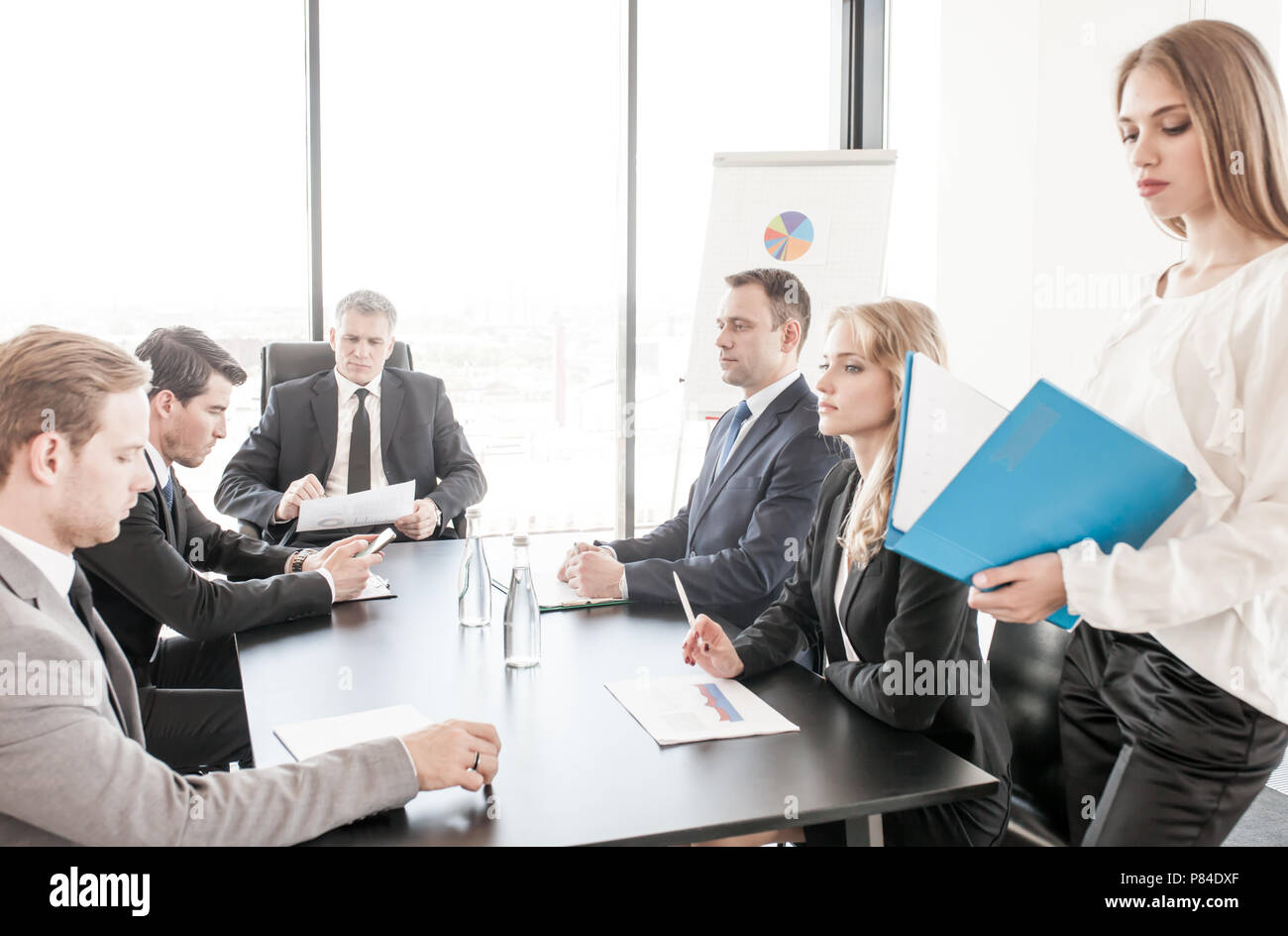 Les gens assis autour de la table de réunion, parler et travailler sur des documents Banque D'Images