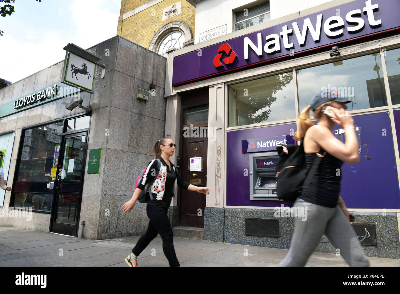 Les gens passent devant les branches de NatWest et banques Lloyds dans Notting Hill Londres Banque D'Images
