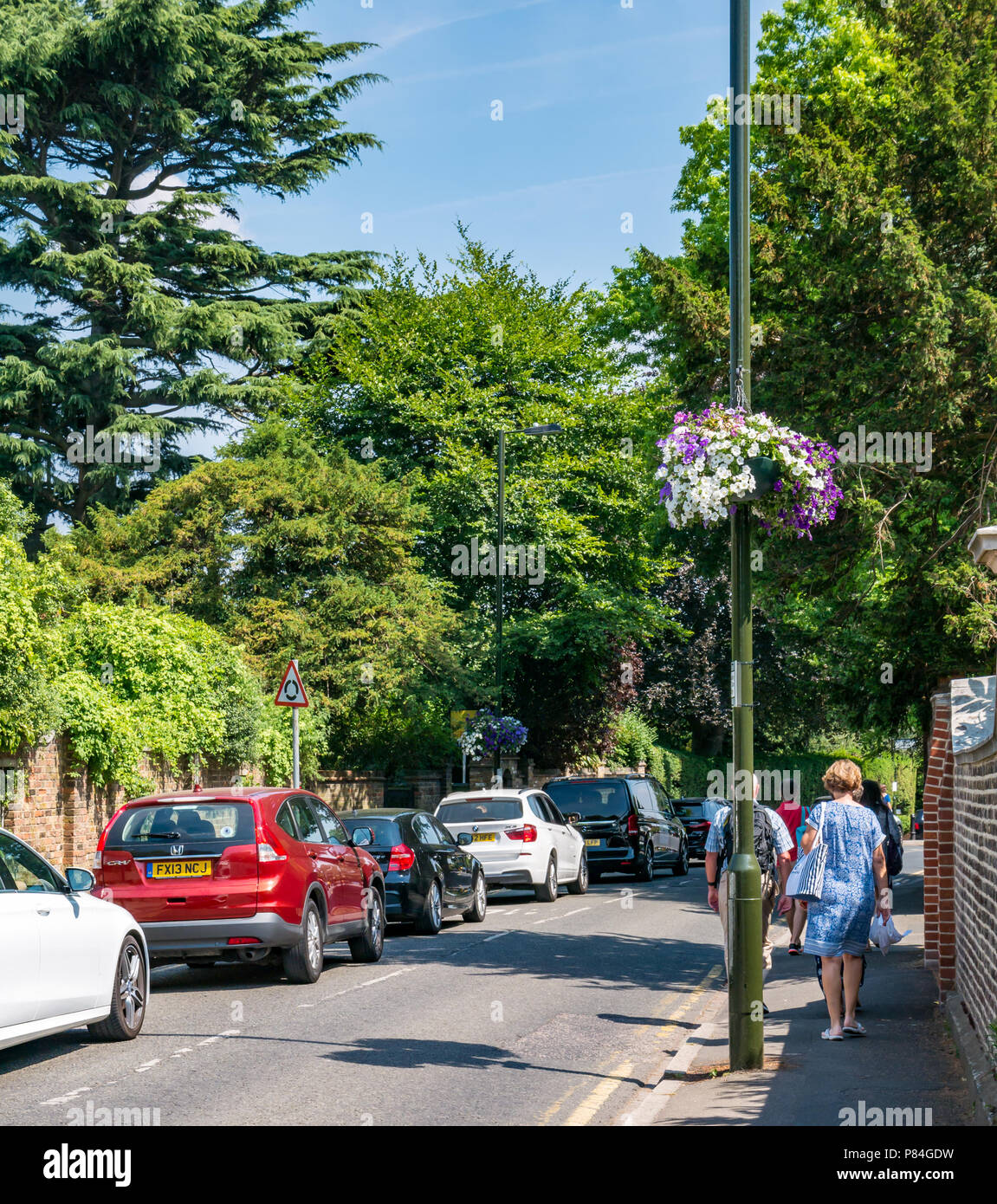Paniers de fleurs suspendus à Wimbledon couleurs de pourpre et de blanc avec des personnes à pied & car embouteillage lors du championnat de tennis, London, England, UK Banque D'Images