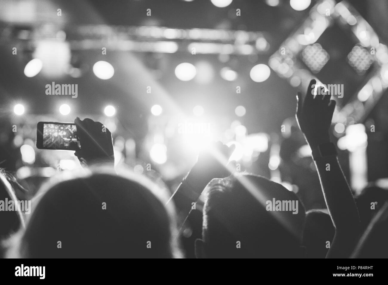 Audience avec les mains posées à un festival de musique et de lumières sur de au-dessus de la scène. Soft focus, troubles de mouvement. Noir et blanc. Banque D'Images