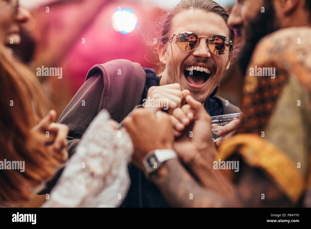 Cheerful man dancing with friends at music festival. Groupe de personnes ayant un grand temps au festival de musique. Banque D'Images