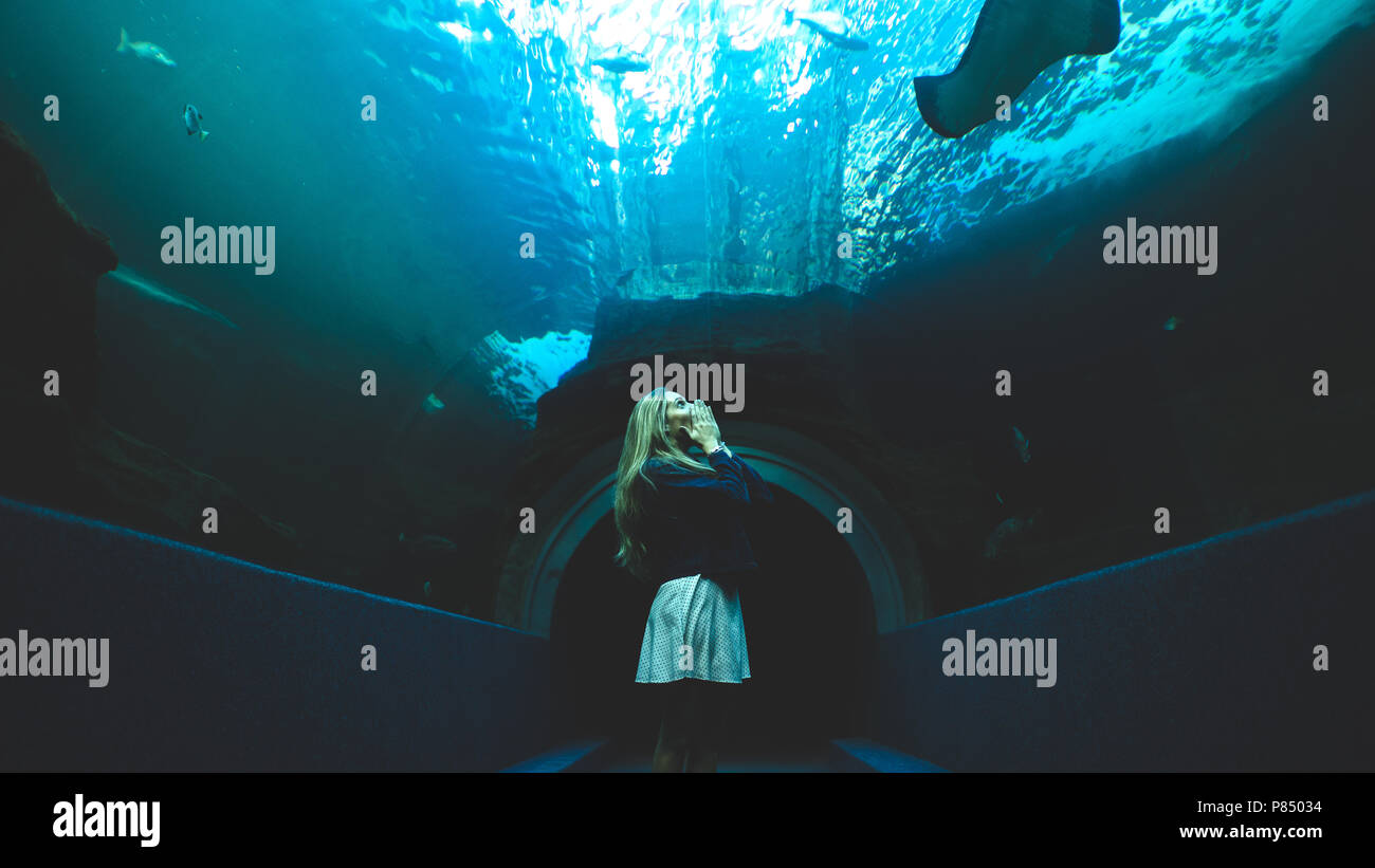 Femme debout dans un passage sous l'eau dans un aquarium. Visite touristique belle attraction. Banque D'Images
