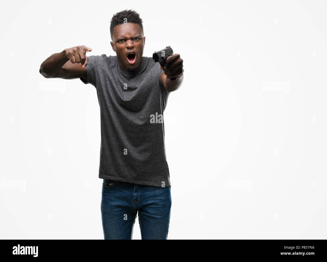 Young african american man holding a gun contrarié et frustré de crier avec colère, fou et hurlant de main levée, la colère concept Banque D'Images