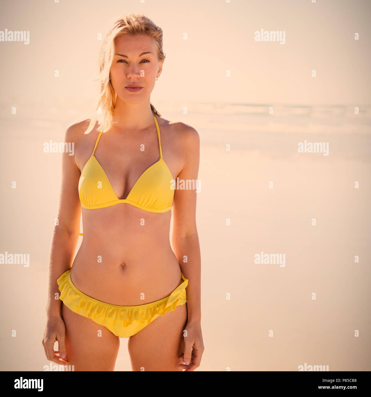 Portrait of young woman in bikini jaune debout à beach Banque D'Images