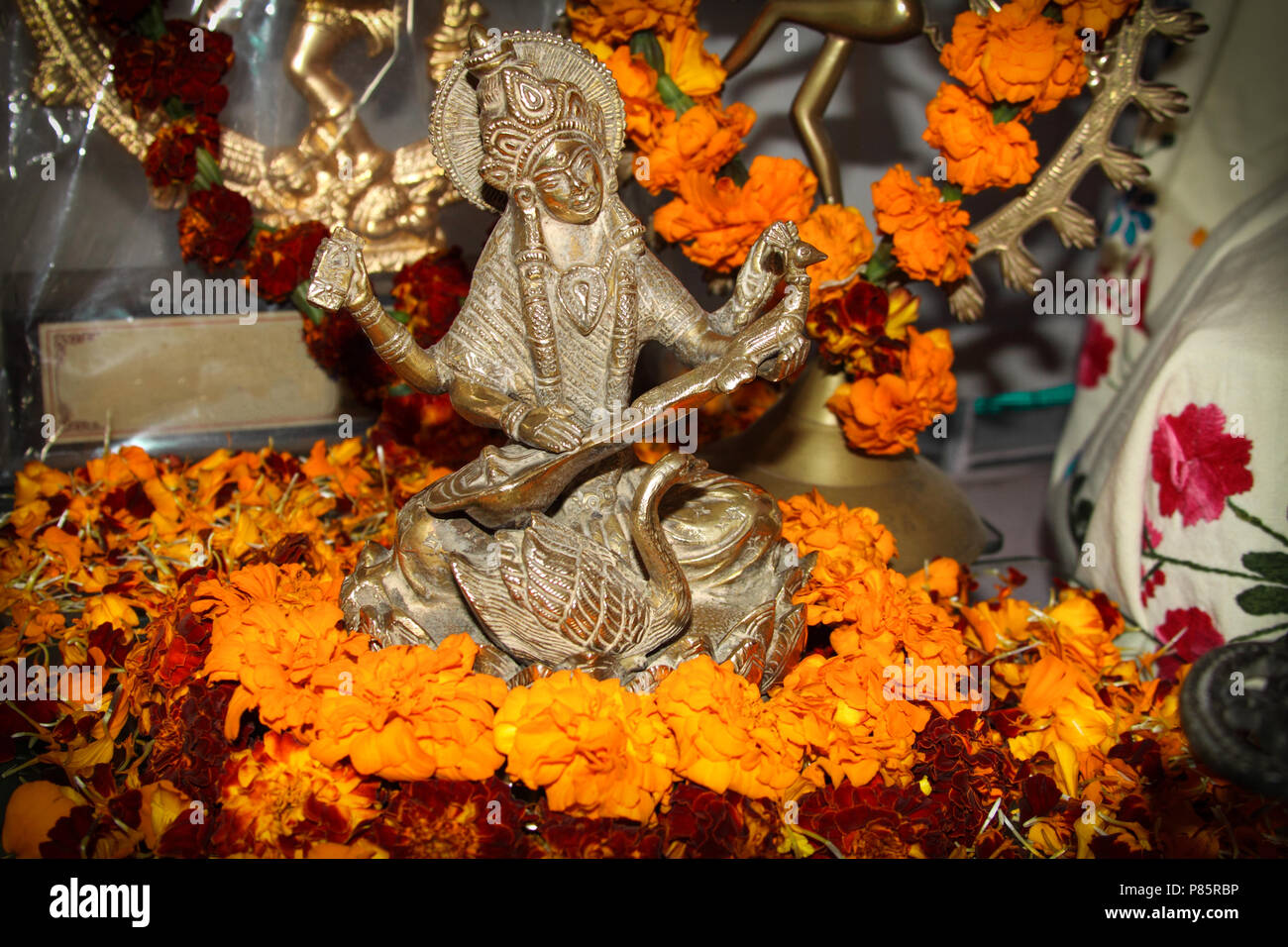 La figure de la Déesse Saraswati. Puja hindoue. L'encens, des offrandes, pétales, fleurs de souci. Indien, traditionnel, autel, religion, vacances, Navratri, still life. Banque D'Images