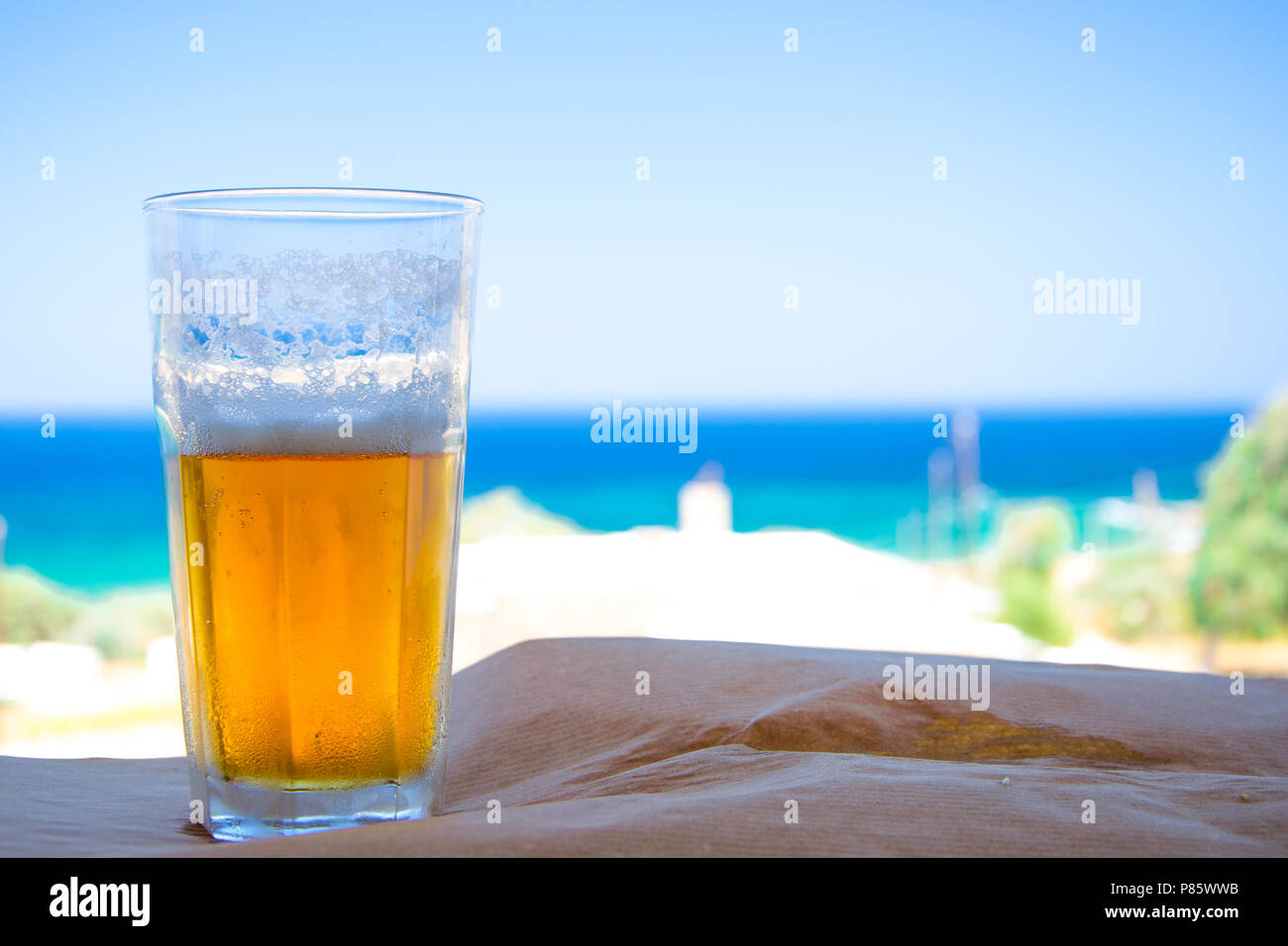 Verre de bière froide sur fond flou sur la mer Égée, Grèce. Banque D'Images
