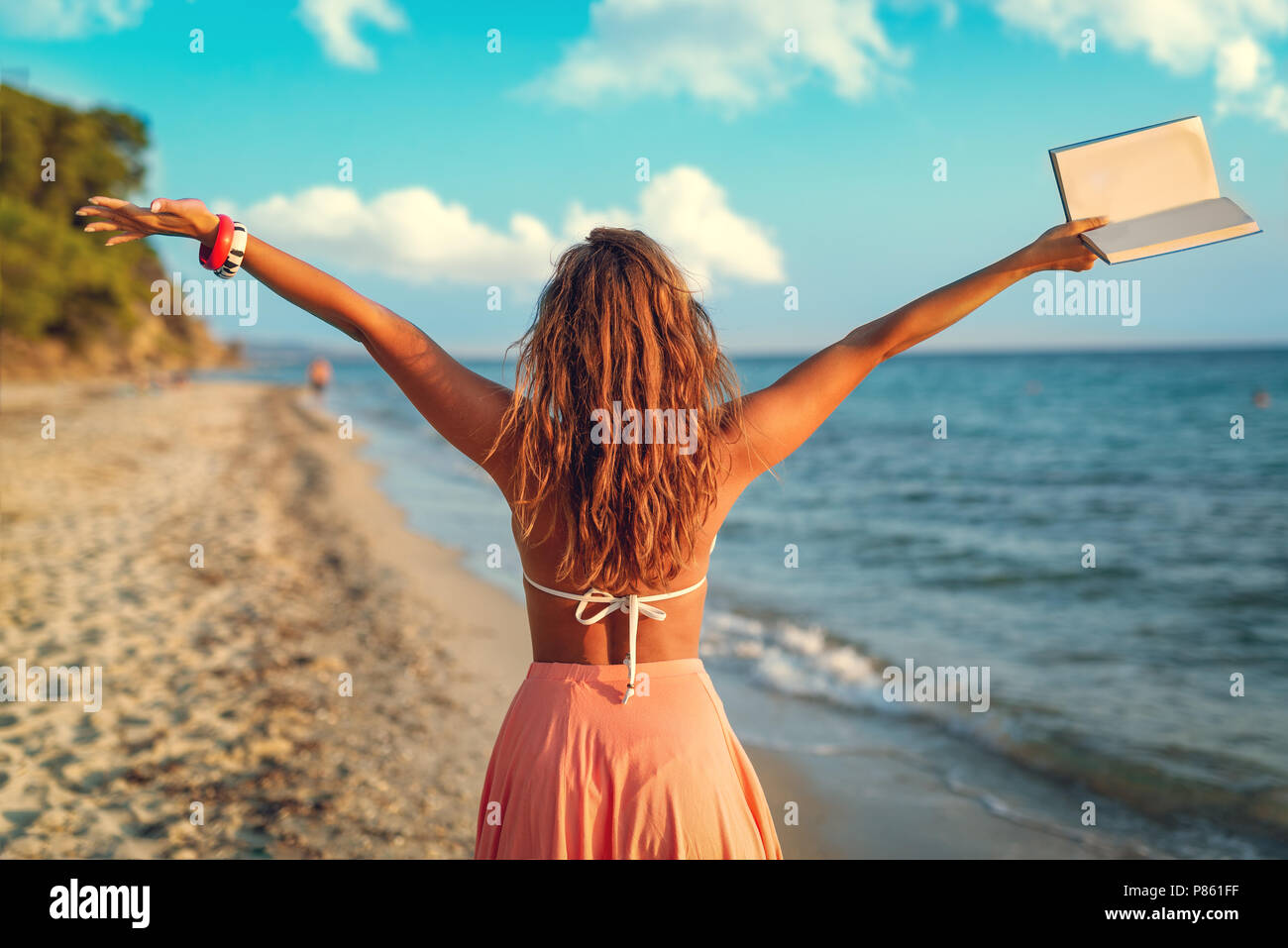 Vue arrière d'une belle jeune femme jouissant sur la plage avec des adresses de son bras ouverts. Banque D'Images