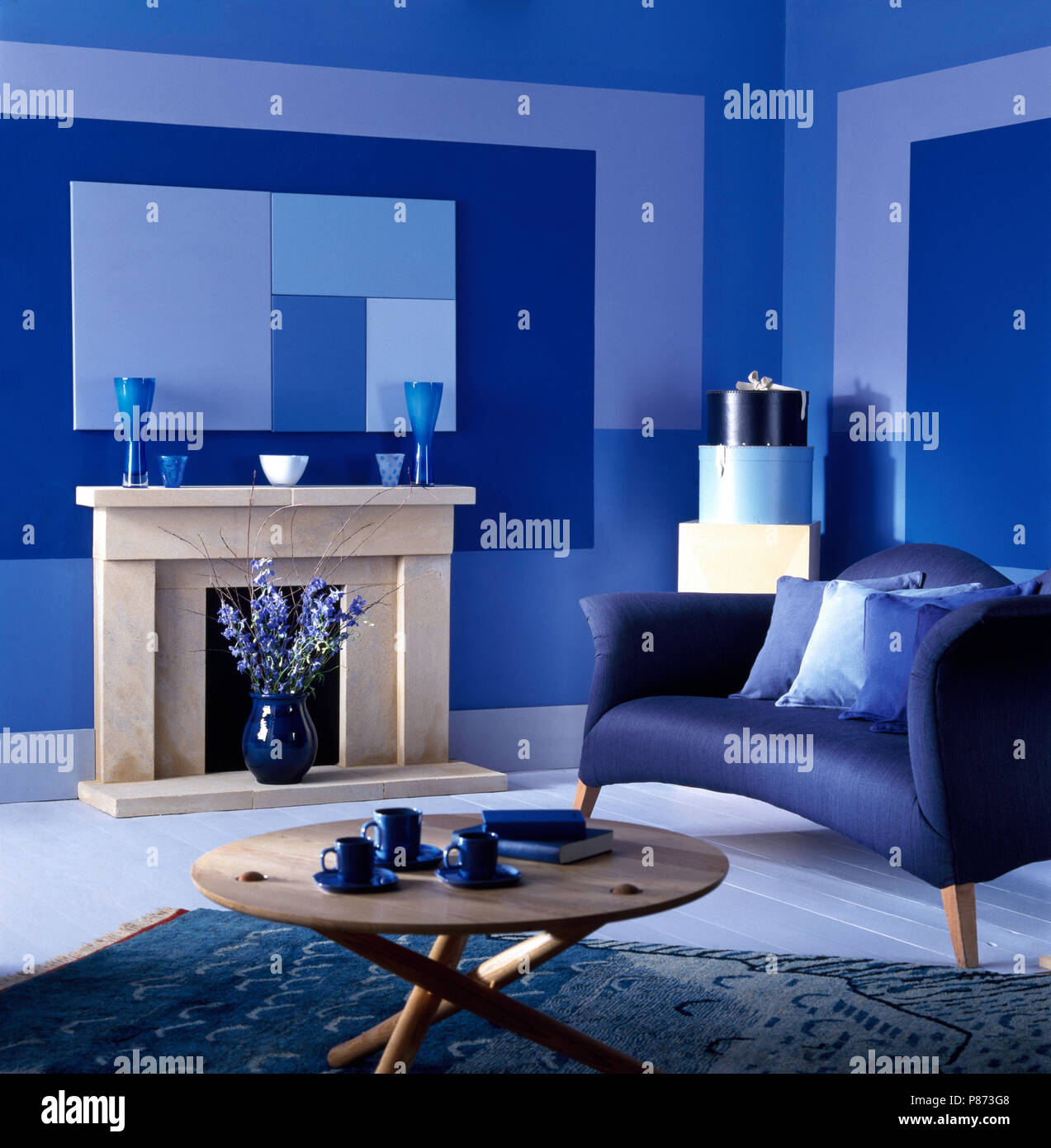 Canapé bleu et une table basse en bois clair dans un salon bleu peint dans  des rectangles Photo Stock - Alamy