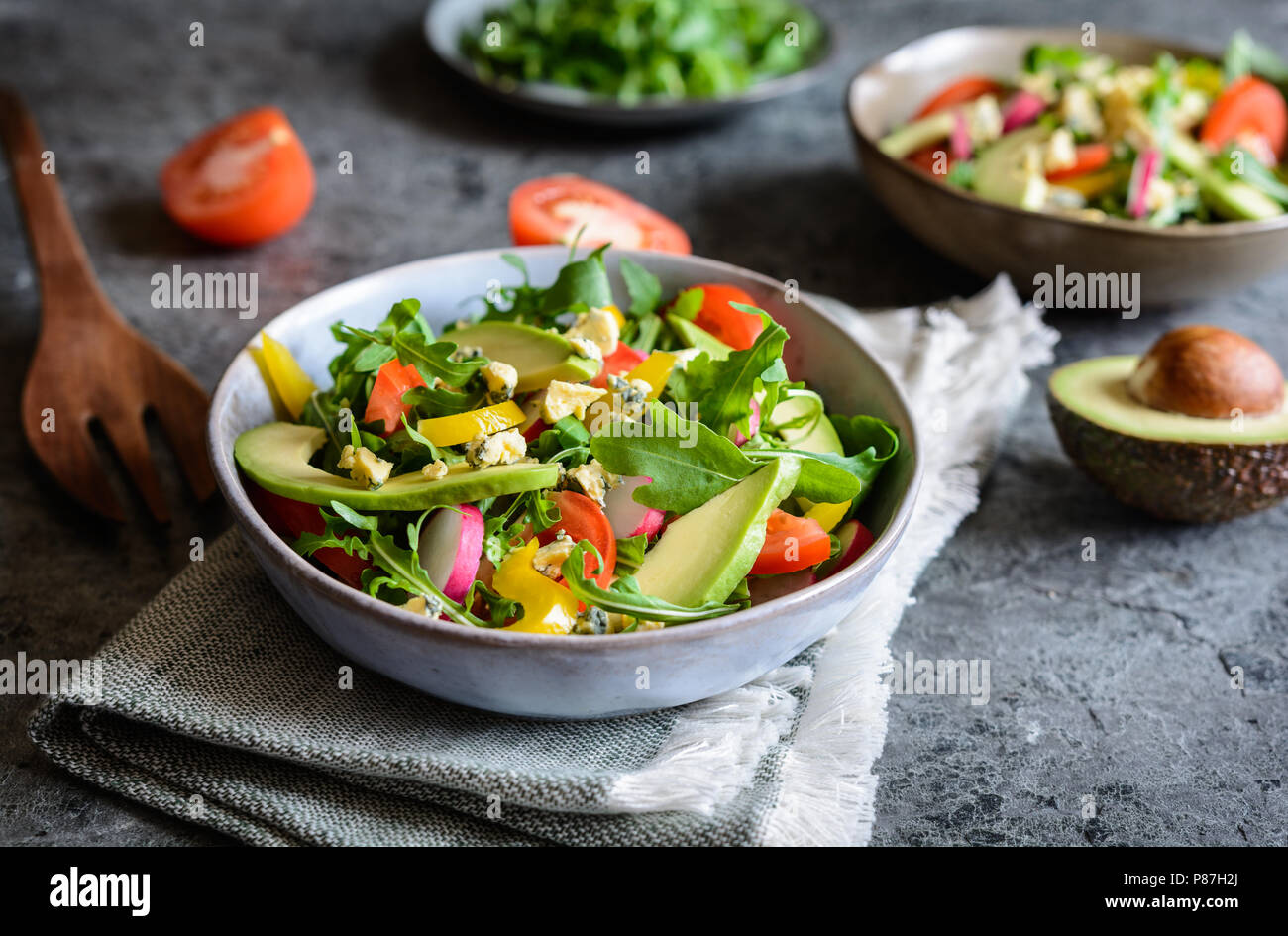 Matières premières en bonne santé avec de l'avocat salade de roquette, radis, poivrons, tomates et fromage de Roquefort Banque D'Images