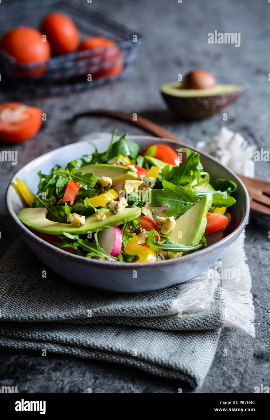 Matières premières en bonne santé avec de l'avocat salade de roquette, radis, poivrons, tomates et fromage de Roquefort Banque D'Images