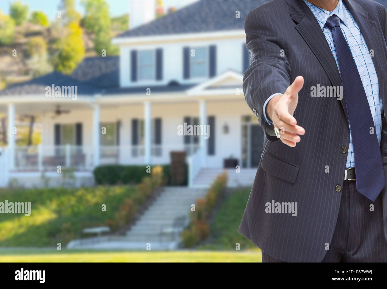 L'agent masculin atteignant pour agiter la main en face de belle nouvelle maison. Banque D'Images