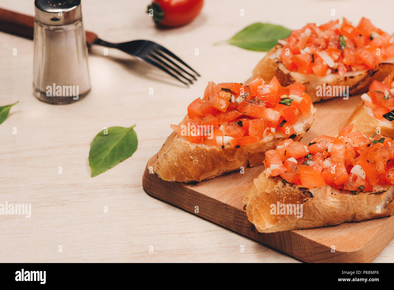 Bruschetta italienne de tomates rôties, de mozzarella et d'herbes sur une planche à découper Banque D'Images