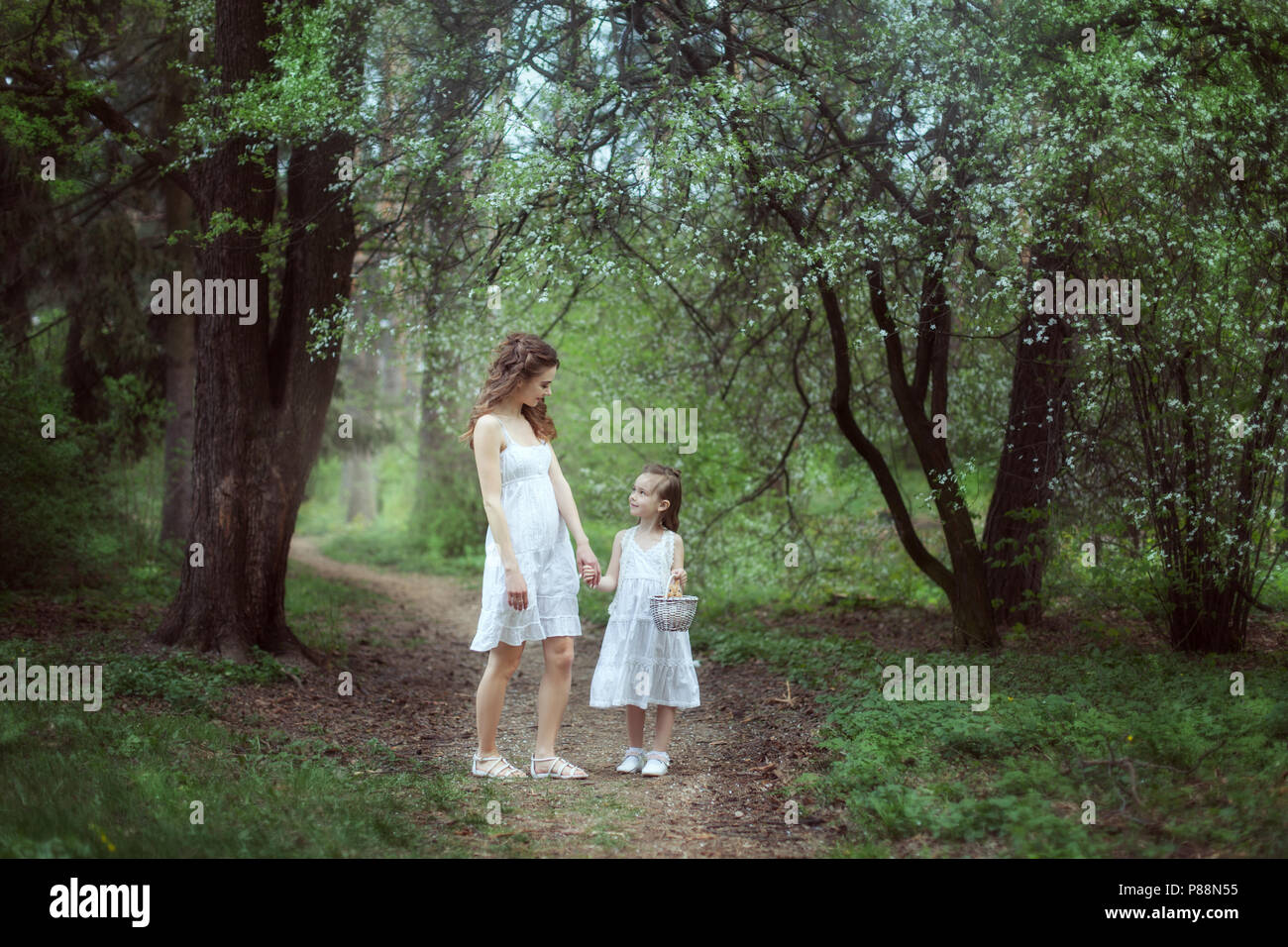 Mère et fille dans une forêt féerique. Dans les mains de la jeune fille un panier avec un lapin. Banque D'Images