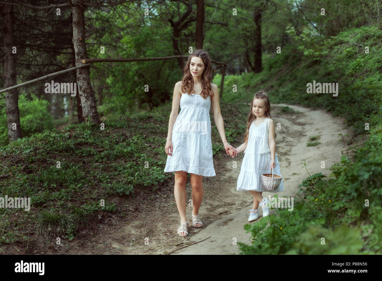 Jeune maman avec sa fille va sur un sentier dans les bois. Banque D'Images