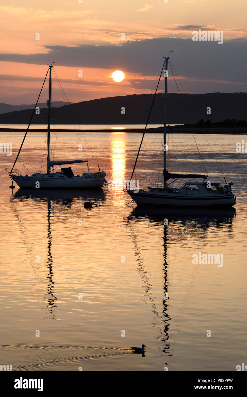 Plein soleil ball reflétant sur l'eau d'Ardmucknish à North Bay et l'aéroport Oban Connel avec voiliers et mouette en silhouette Banque D'Images