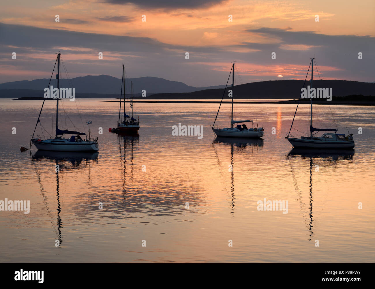 Ciel rouge et les nuages au coucher du soleil reflétant sur l'eau d'Ardmucknish à North Bay Connel avec voiliers et l'île de Lismore en silhouette Banque D'Images