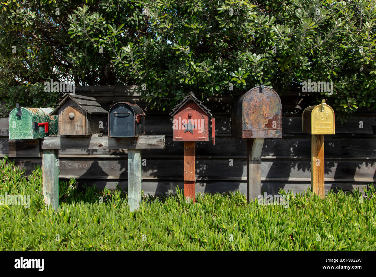 Une gamme de différents styles de boîtes aux lettres le long d'un mur de jardin en plein air à Monterey, Californie Banque D'Images