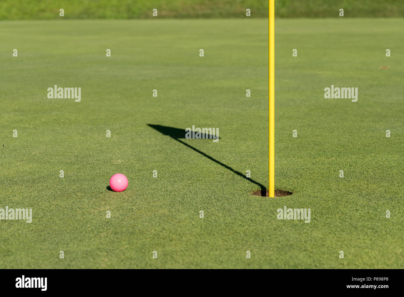 Balle de golf rose par pavillon et trou sur putting green Banque D'Images
