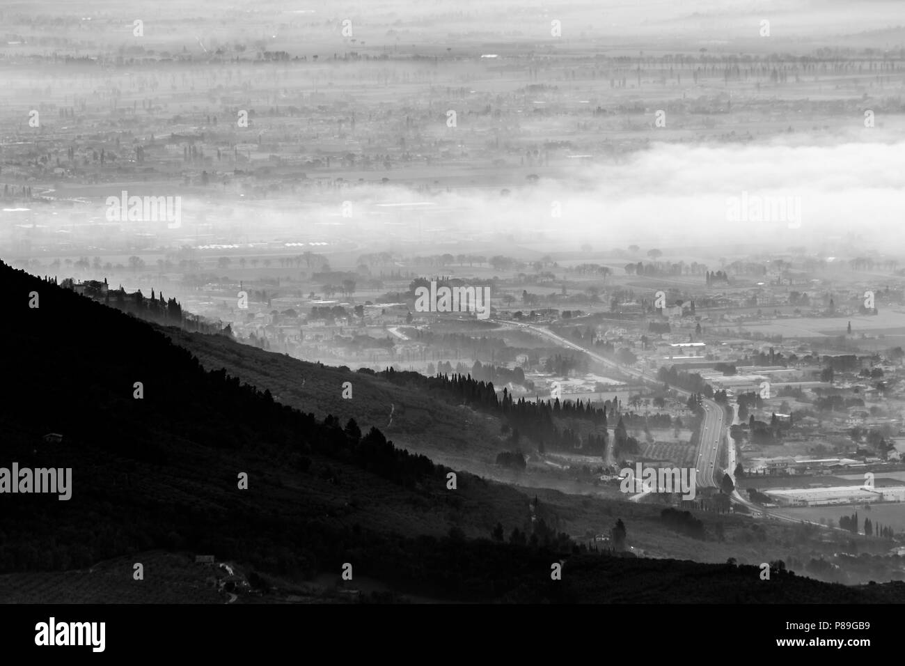 Belle vue aérienne de la vallée de l'Ombrie dans un matin d'hiver, avec du brouillard couvrant les arbres, maisons et rues Banque D'Images