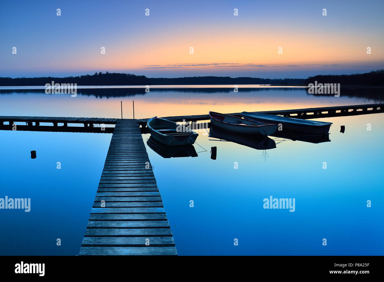 Crépuscule au lac Schaalsee, jetée en bois avec des bateaux de pêche, Mecklembourg-Poméranie-Occidentale, Allemagne Banque D'Images