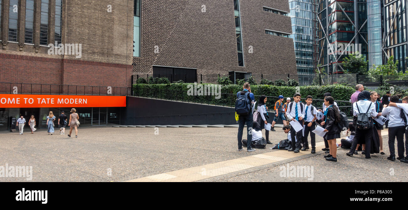 Les visiteurs entrant et quittant le Tate Modern Gallery tandis qu'un groupe d'école attend avec une feuille à la main, avec leurs enseignants, prêt à aller dans Banque D'Images