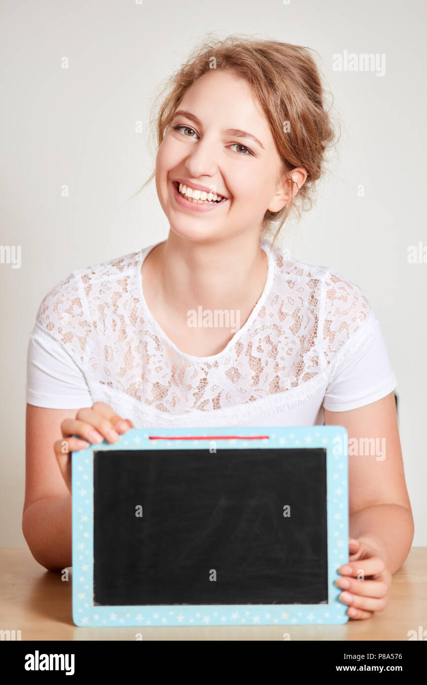 Smiling young woman is holding a blank blackboard dans ses mains Banque D'Images