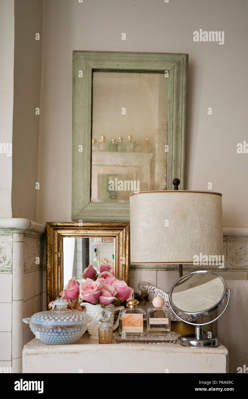 Une sélection de miroirs et de parfums sur le cabinet en shabby chic salle de bains carrelée Banque D'Images