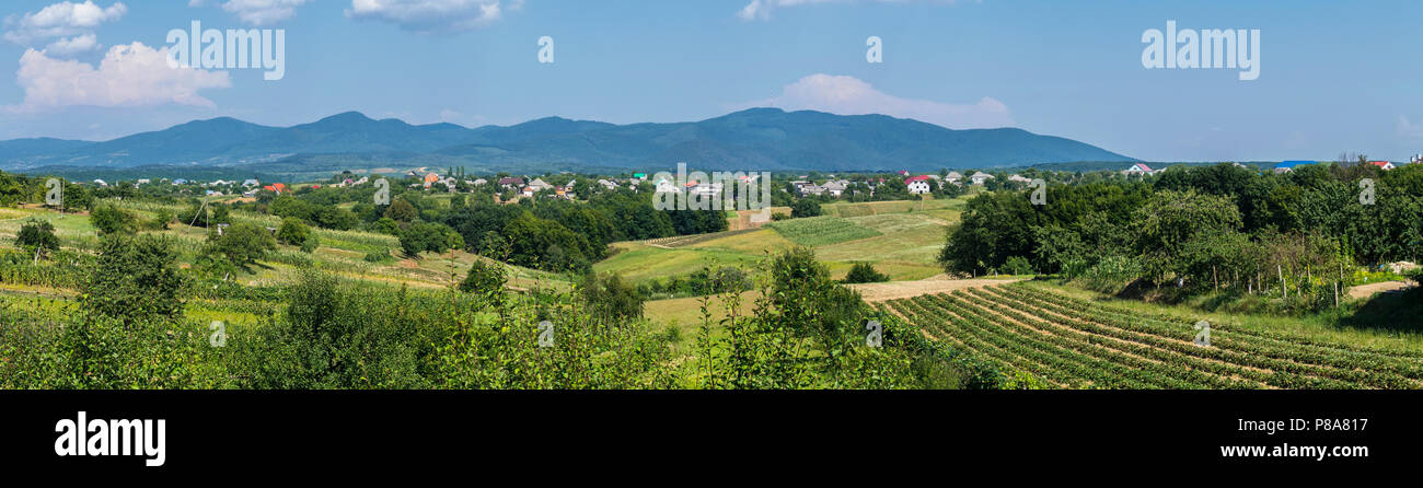 Un panorama de collines avec des terres agricoles près du village de l'arrière-plan de la montagnes lointaines . Pour votre conception Banque D'Images